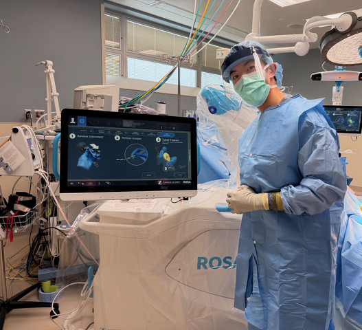 Dr. Daniel Li stands next to the ROSA robotic system he used for a knee replacement